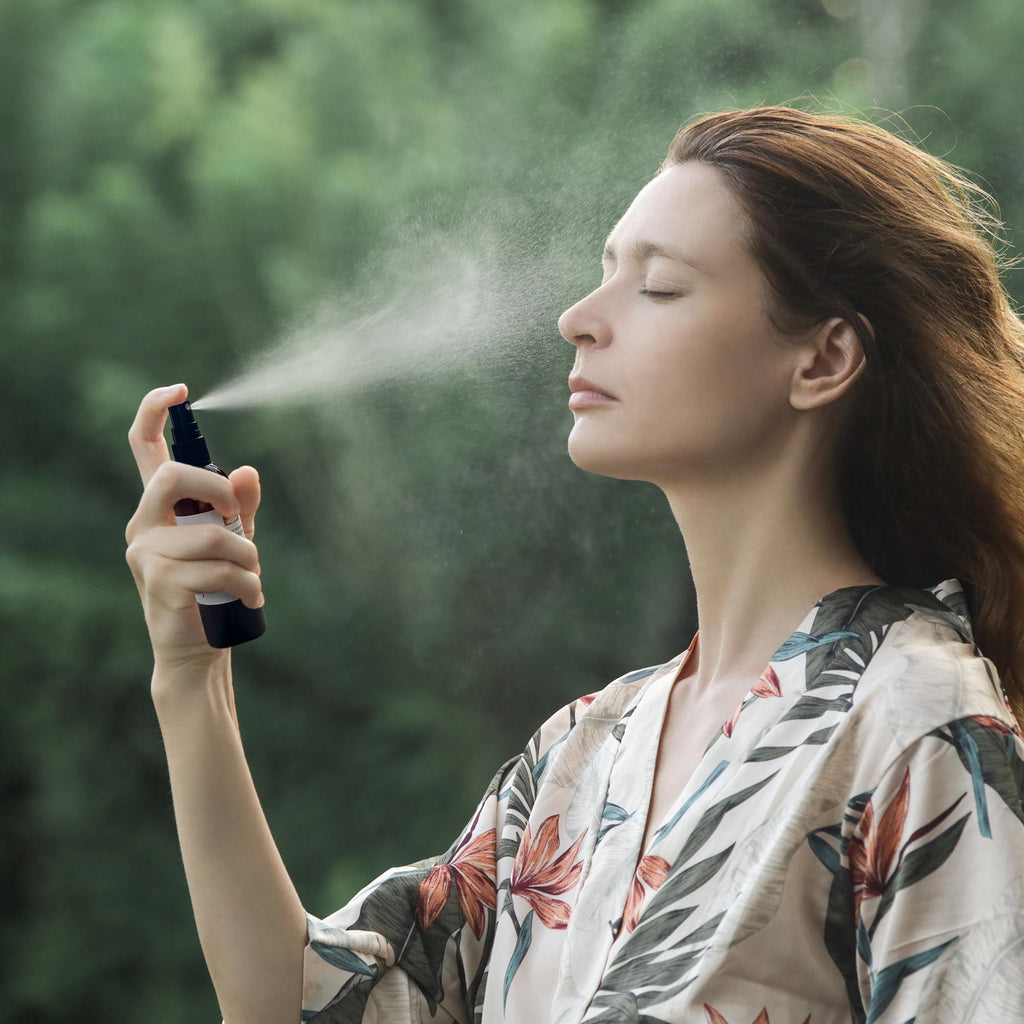 A woman praying rose water on her face.